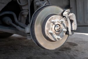 Exposed car brake disc and caliper during a maintenance check, showing wear and tear.