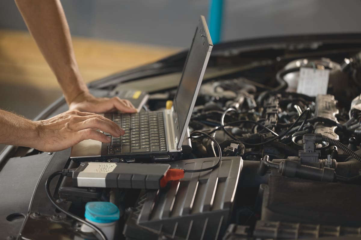 A close up of a mechanic performing engine tuning on a car's engine.