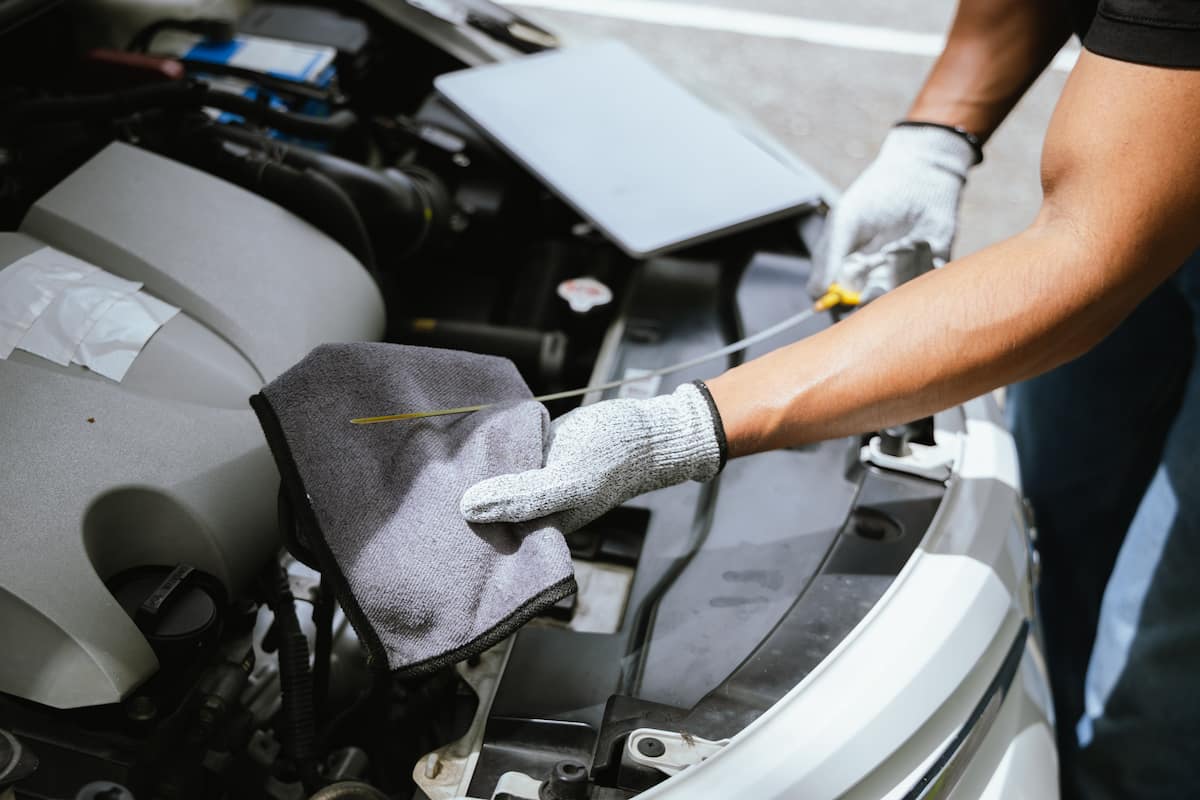 A mechanic in the Rossi mechanical Kelmscott workshop, checking the oil filter in a car.